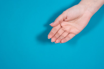 Closeup top view of one cupped empty female hand isolated on blue background.