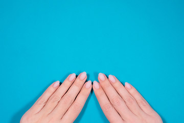 Closeup top view of two female hands with beautiful fresh professional manicure and classic natural pink pastel nail design with mat top cover without shine and gloss.