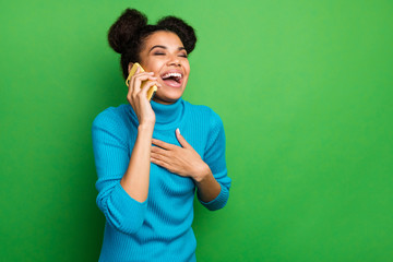 Poster - Photo of funny excited dark skin lady hold telephone speaking chatting with friends listen humorous story laughing out loud wear blue turtleneck isolated green color background