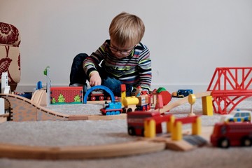 boy playing with wooden toy trains