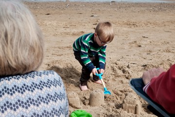 Boy playing at the beach building sand castles