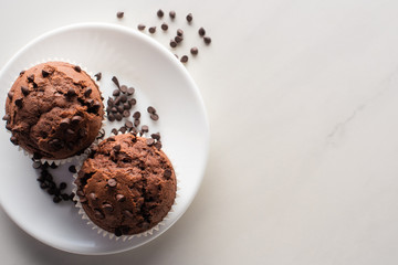 Wall Mural - top view of fresh chocolate muffins on white plate on marble surface