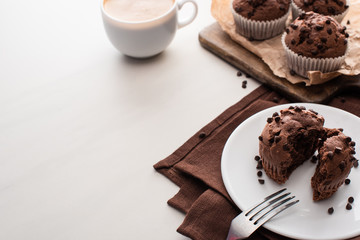 Sticker - fresh chocolate muffins on wooden cutting board near plate with fork and coffee