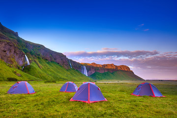 Wall Mural - Camping tents near Seljalandsfoss. One of the most beautiful waterfalls on the Iceland, Europe. Popular and famous tourist attraction summer holiday destination in on South Iceland. Travel postcard.