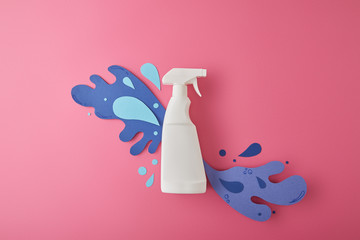 composition with spray bottle and blue water splashes made of paper, on pink