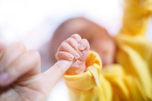 Newborn Baby Touching His Mother Hand, Baby Holding Finger Of His Mother Giving Senses Of Attachment And Bonding. The Image Taken With A Selective Focus Stressing An Emotional Scene.