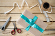 © BarguZina - handmade gift box tie a green bow, a tool for its manufacture on a wooden background, top view, copy space