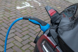 Fototapeta  - Electric vehicle charging station. charging an electric car (EV) with the power cable supply plugged in.