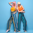 © evgenij918 - Two fashionable girl with stylish hair. Beautiful Adorable young woman in summer colorful outfit, dyed hairstyle, make up. Glamour model sister friend, fashion concept on blue, full-length