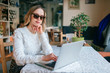 © benevolente - Beautiful young freelancer woman using laptop computer sitting at cafe table. Happy smiling girl working online or studying and learning while using notebook. Freelance work, business people concept