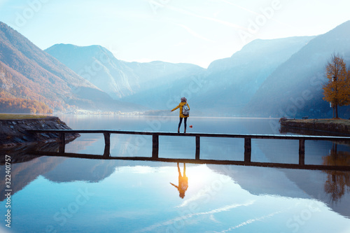 Fotomural tourist girl in a hat and with a backpack sitting on a wooden bridge