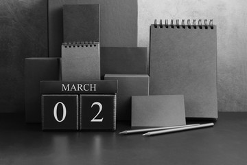 March 2th. Day 2 of month. Wood cube calendar with date month and day. Trendy classic black color. Lot of empty pages template for daily notes.