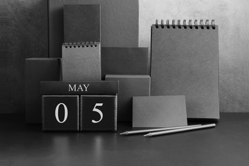 May 5th. Day 5 of month. Wood cube calendar with date month and day. Trendy classic black color. Lot of empty pages template for daily notes.