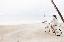 Woman Riding Bicycle On The Beach, Maguhdhuvaa Island, Gaafu Dhaalu Atoll, Maldives
