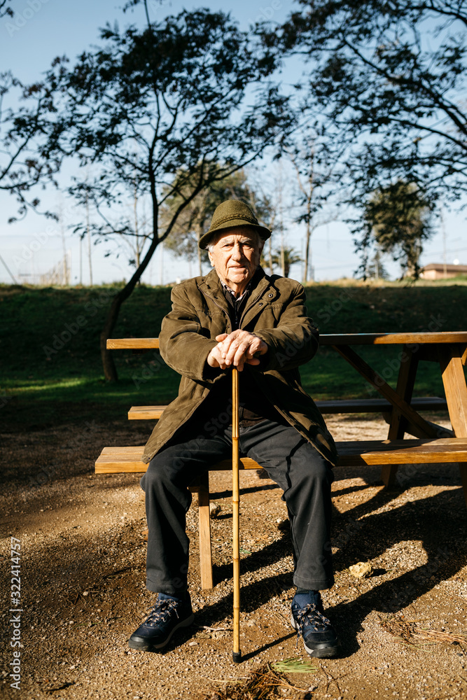 Old man with cane sitting on bench in a park Stock Photo | Adobe Stock