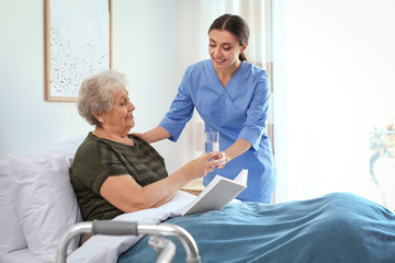 Canvas Print - Care worker giving water to elderly woman in geriatric hospice