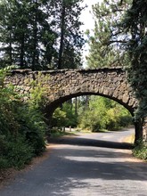 Old Stone Bridge In A Park Surrounded By Green Trees