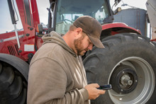 Male Farmer Using Smart Phone Outside Tractor