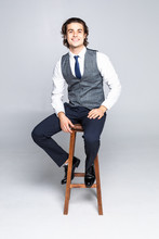 Portrait Of Business Man Sitting On A High Stool And Smiling For The Camera. Isolated On A White Background