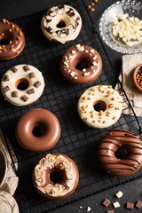 Vertical shot of delicious donuts covered in the white and brown chocolate glaze on a black table