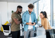 © Sanja - A man is showing something on his phone to his co-workers in a casual work-style office.