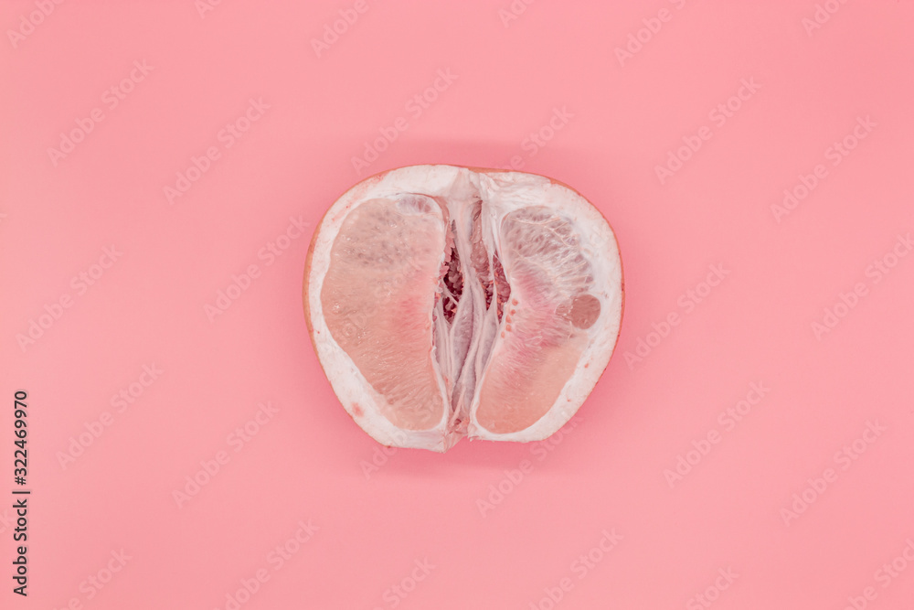 Sliced pomelo on a pink background, the concept of a female vagina - obrazy, fototapety, plakaty 