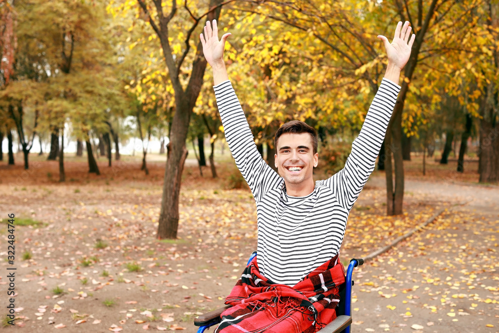 Happy handicapped young man in autumn park