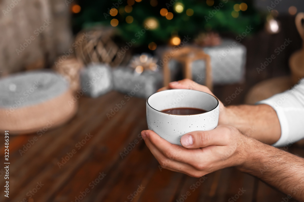 Man with cup of hot chocolate at home, closeup