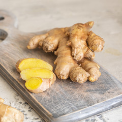 Ginger roots and ginger root sliced on cut board. Ginger used as spice for food and treatment in alternative medicine.