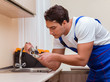 © Elnur - Young repairman working at the kitchen
