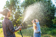 young happy beautiful couple hosing in the garden, summer happiness and love concept, poured water from a garden hose of a spray