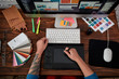 © Svitlana - Professional web illustrator. Top view of a graphic designer using graphic tablet and computer in the office or studio. Workplace with graphic tablet, keyboard, computer and color swatches