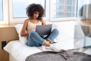 Wall Mural - African woman indoors at home using laptop computer.