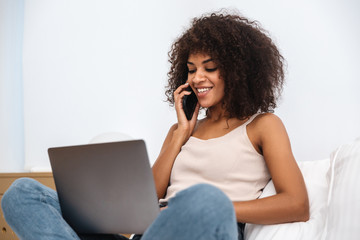 Sticker - African woman indoors at home using laptop computer.