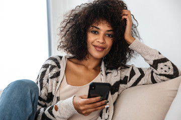 Wall Mural - Woman indoors at home using mobile phone.