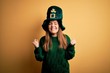 © Krakenimages.com - Young beautiful brunette woman wearing green hat on st patricks day celebration very happy and excited doing winner gesture with arms raised, smiling and screaming for success. Celebration concept.