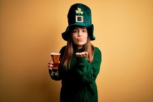 Young Beautiful Woman Wearing Green Hat Drinking Glass Of Beer On Saint Patricks Day Looking At The Camera Blowing A Kiss With Hand On Air Being Lovely And Sexy. Love Expression.