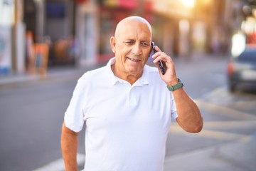 Senior handsome man smiling happy and confident. Standing with smile on face talking by the phone at town street