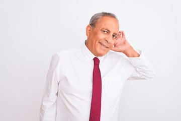 Wall Mural - Senior grey-haired businessman wearing elegant tie over isolated white background smiling with hand over ear listening an hearing to rumor or gossip. Deafness concept.