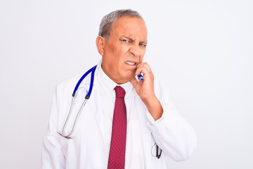 Sticker - Senior grey-haired doctor man wearing stethoscope standing over isolated white background looking stressed and nervous with hands on mouth biting nails. Anxiety problem.