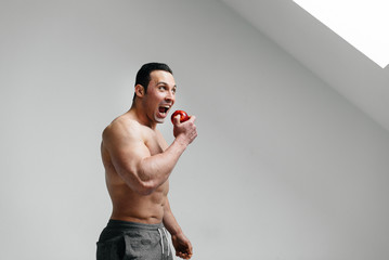 Sporty sexy guy eating fruit on a white background. Diet. Healthy diet