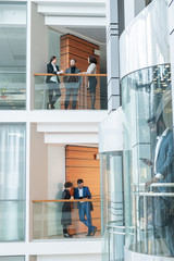Aufkleber - Young office employee standing on balconies and discussing work in modern financial district