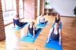 © Krakenimages.com - Young beautiful group of sportswomen practicing yoga. Coach teaching upward-facing dog pose to sporty women at gym