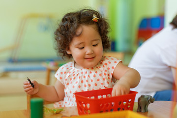 Pretty little kazakh girl sitting by the table and studying school lessons. Developing knowledge. Montessori education