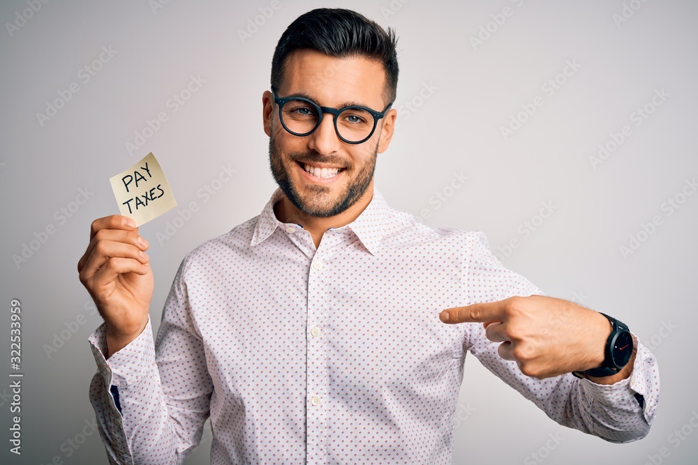 Reminder Man Young handsome man holding reminder paper with pay taxes message over ...