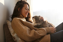 Portrait Of Young Woman Holding Cute Siberian Cat With Green Eyes. Female Hugging Her Cute Long Hair Kitty. Background, Copy Space, Close Up. Adorable Domestic Pet Concept.