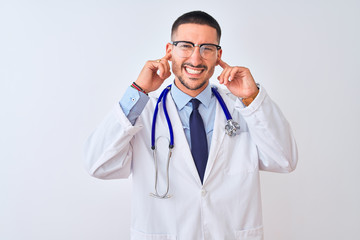 Poster - young doctor man wearing stethoscope over isolated background covering ears with fingers with annoye