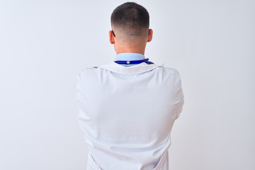 Wall Mural - Young doctor man wearing stethoscope over isolated background standing backwards looking away with crossed arms