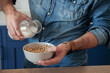 © Space_Cat - Pouring milk in cereals or porridge. Milk is poured in a ceramic bowl with baked granola. Healthy vegetarian breakfast.