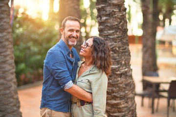 Middle age beautiful couple smiling happy and confident at town park. Standing with smile on face and hugging